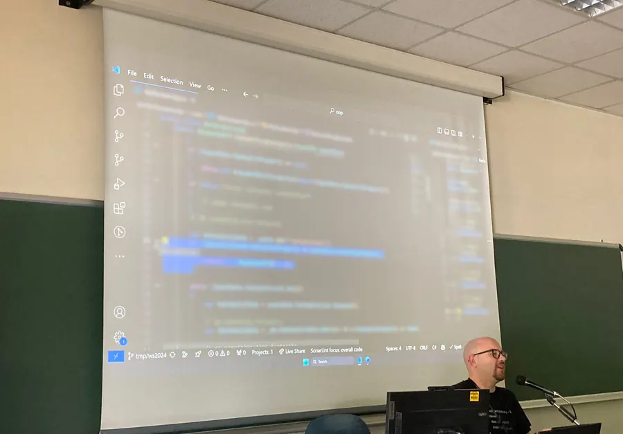A technical training room: code projected on the wall and the instructor at the desk.